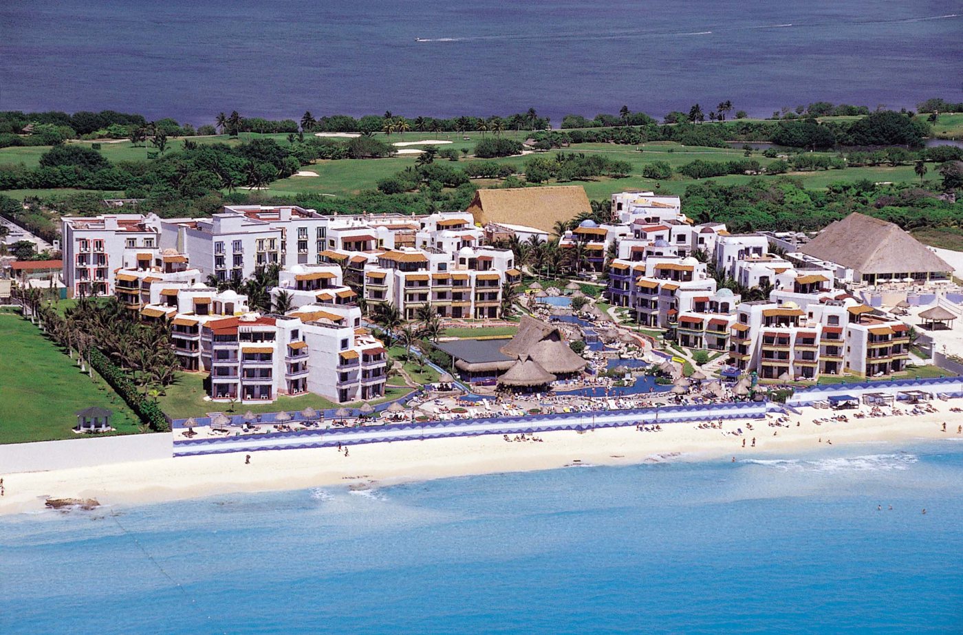 El Pueblito Beach Hotel from the air: white village-style buildings between the beach and the golf course by the lagoon
